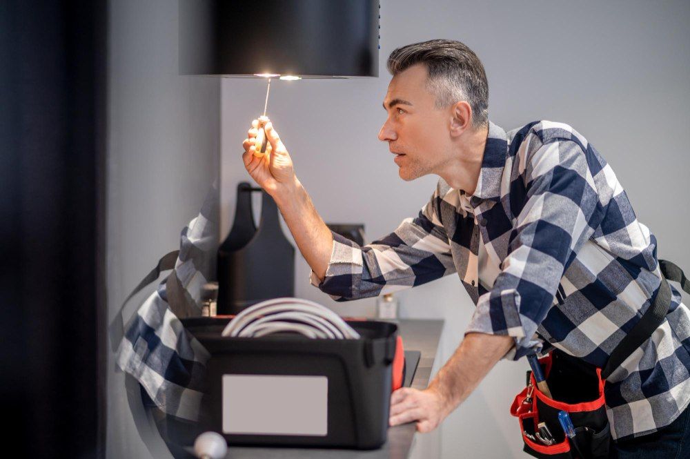 électricien en train de changer une ampoule de hotte