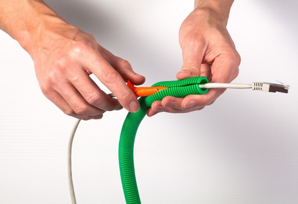 paire de mains qui fait passer un câble Ethernet dans la gaine fendue