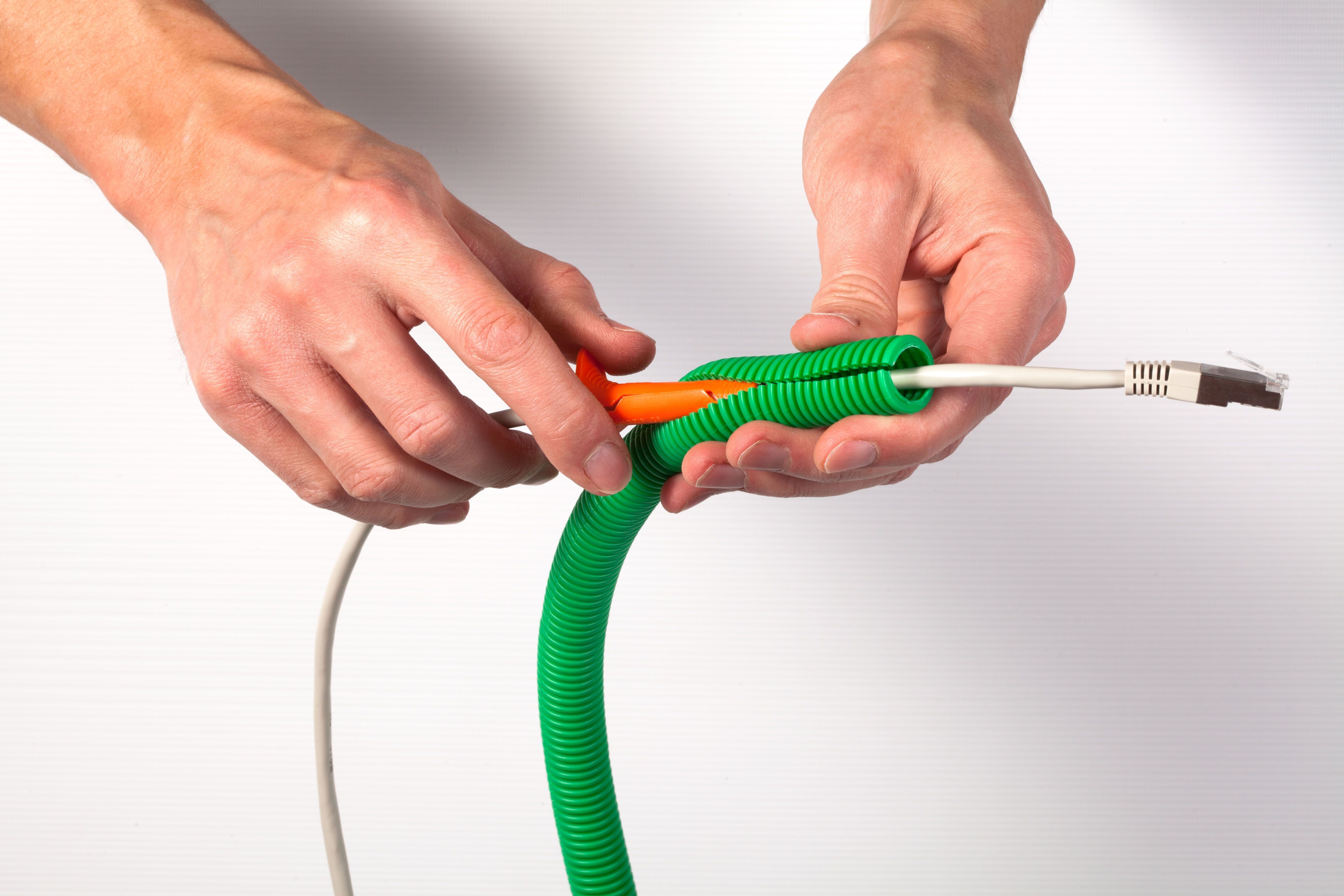 paire de mains qui fait passer un câble Ethernet dans la gaine fendue